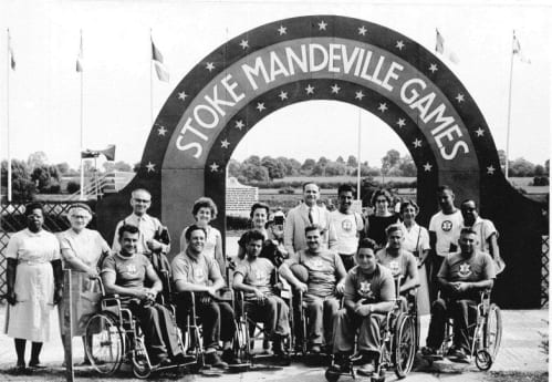 Wheelchair basketball team, nurses and doctors under the Stoke Mandeville Games archway in the 1960s
