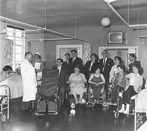 Professor Sir Ludwig Guttmann and the patients receiving a wheelchair