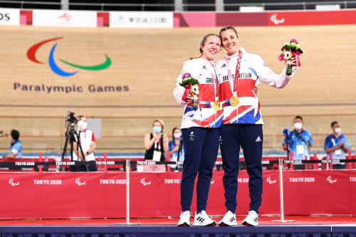 Lora Fachie, Paralympic cyclist, with her sighted partner and their gold medals at the Tokyo 2020 Paralympics.