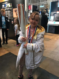 Young person with Paralympic torch, medal and jacket